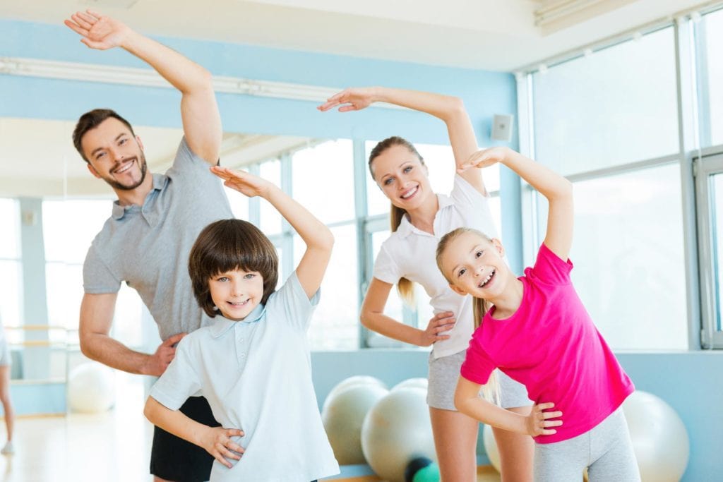 Family exercising. Happy sporty family doing stretching exercises in sports club